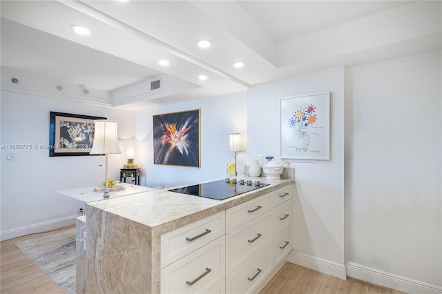 kitchen with black electric stovetop, light hardwood / wood-style floors, white cabinets, kitchen peninsula, and a raised ceiling