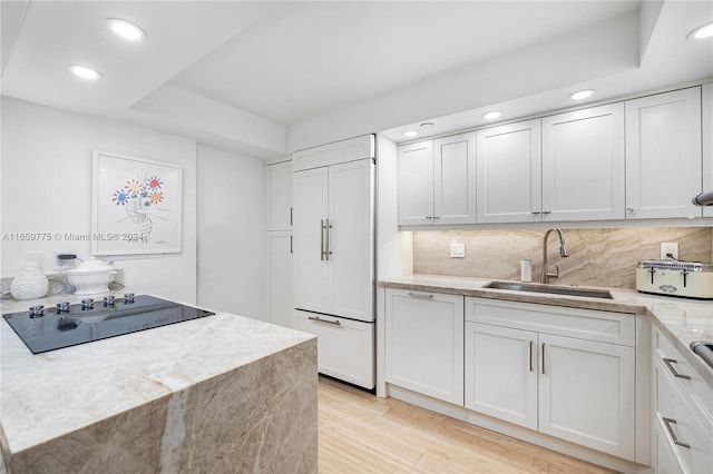 kitchen featuring decorative backsplash, white cabinets, light hardwood / wood-style flooring, sink, and paneled fridge