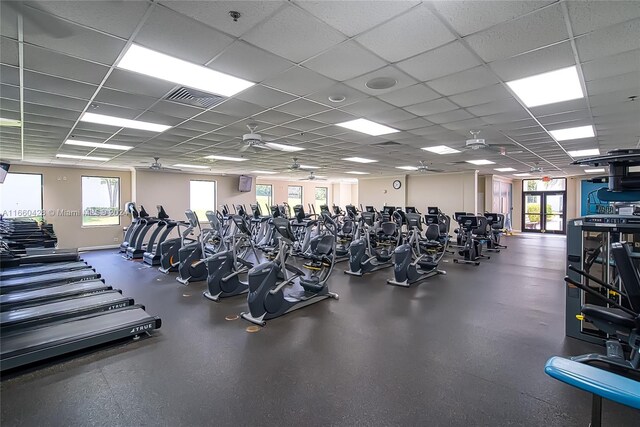 gym featuring a drop ceiling, ceiling fan, and plenty of natural light