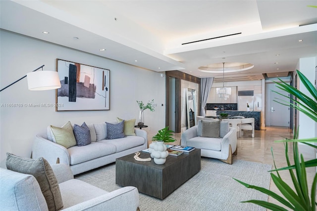 living room with a notable chandelier and a raised ceiling