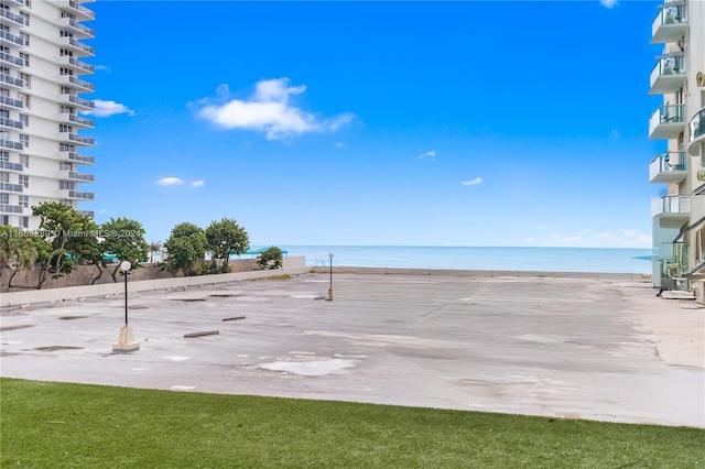 surrounding community featuring a lawn, a water view, and a view of the beach