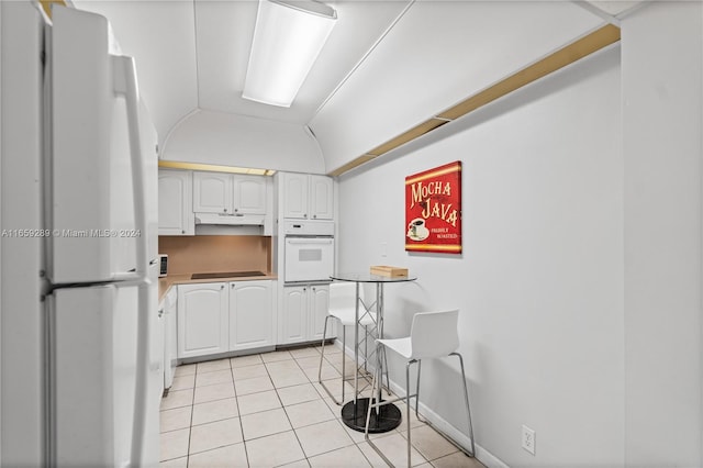 kitchen with lofted ceiling, light tile patterned floors, white appliances, and white cabinetry