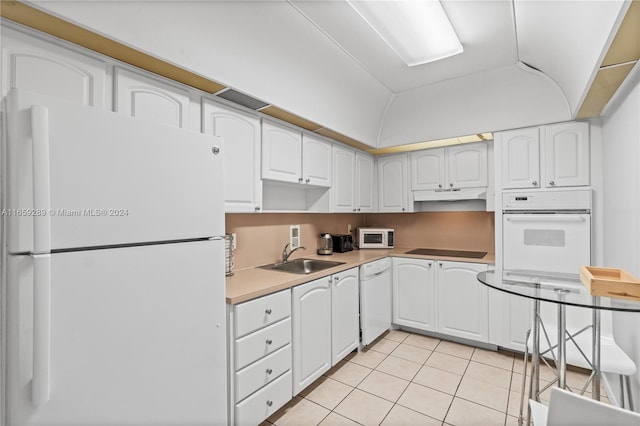 kitchen with light tile patterned flooring, vaulted ceiling, white appliances, and white cabinetry