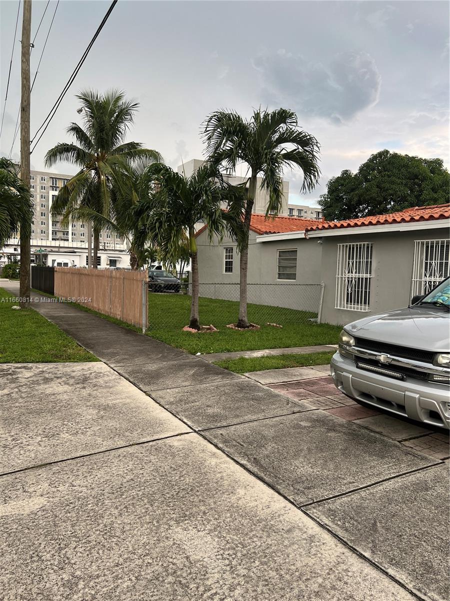 view of side of property featuring fence, a yard, stucco siding, and a tiled roof