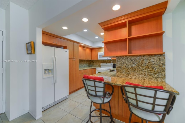 kitchen featuring backsplash, white appliances, kitchen peninsula, light stone countertops, and light tile patterned floors