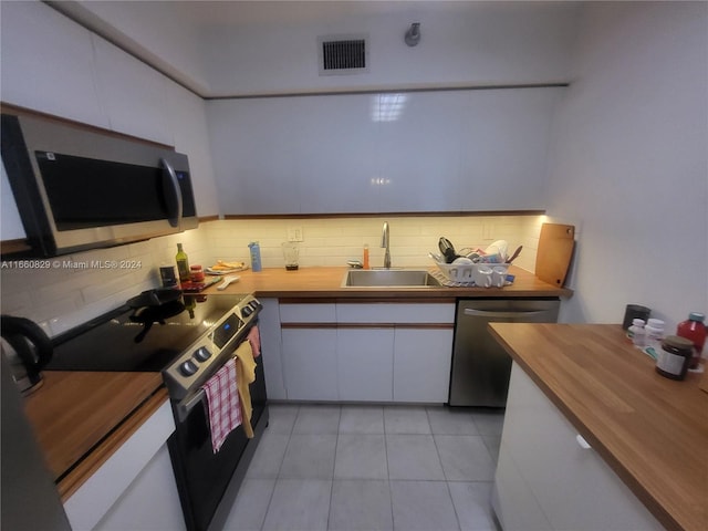 kitchen featuring tasteful backsplash, sink, white cabinetry, butcher block counters, and stainless steel appliances