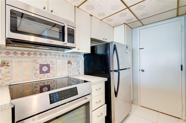 kitchen with stainless steel appliances, white cabinets, light tile patterned flooring, and backsplash