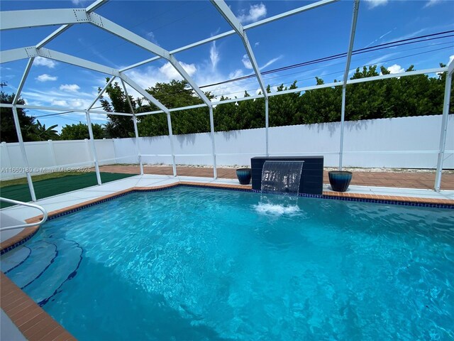 view of swimming pool featuring pool water feature, a lanai, and a patio area