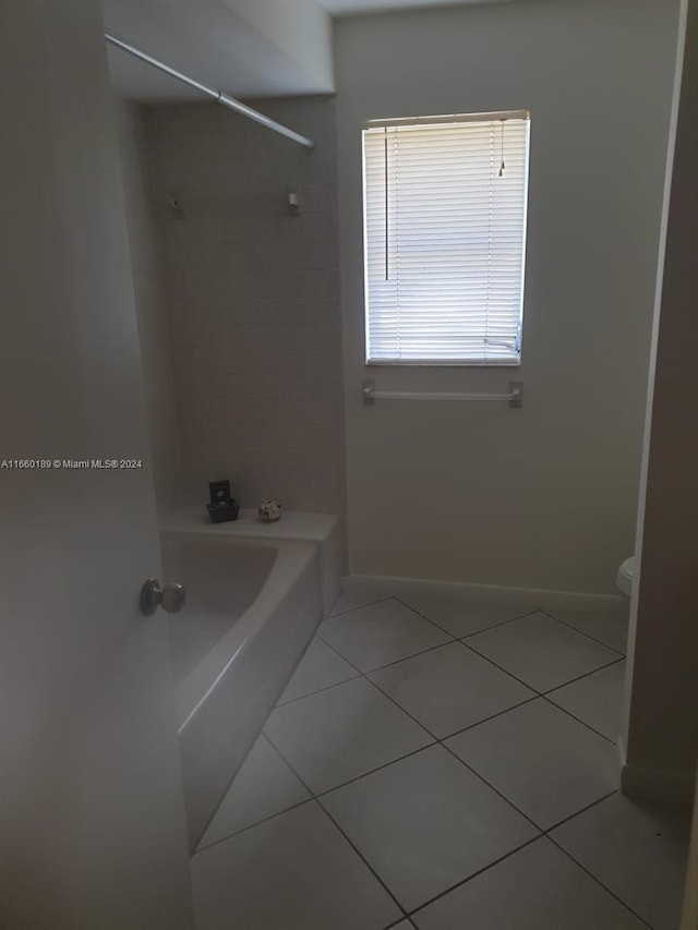 bathroom with tiled shower / bath combo, tile patterned floors, and toilet