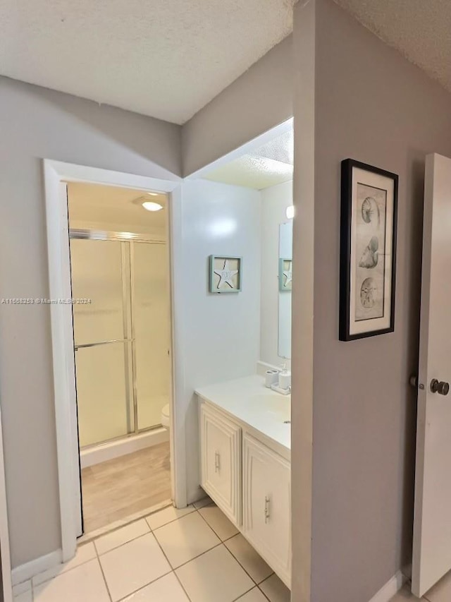 bathroom with a textured ceiling, an enclosed shower, tile patterned floors, vanity, and toilet