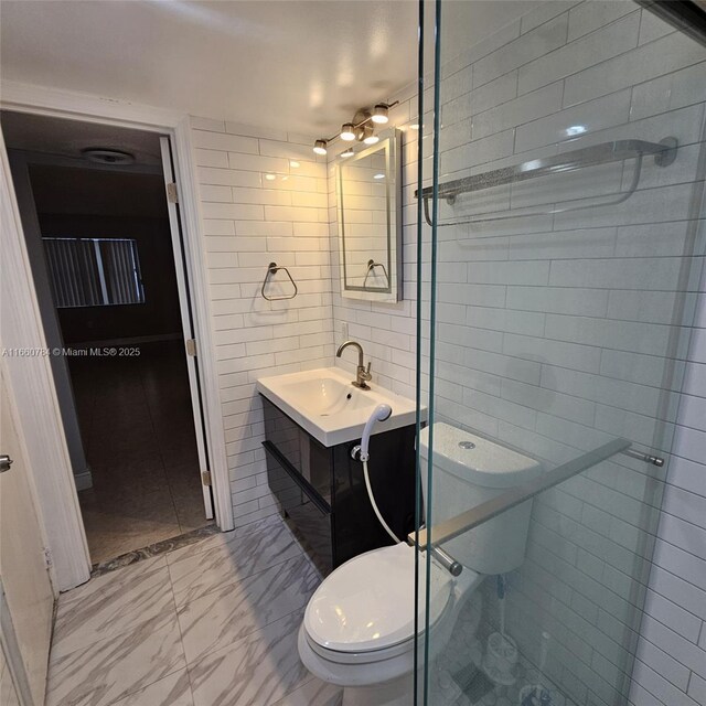 bathroom with vanity, toilet, and tile walls