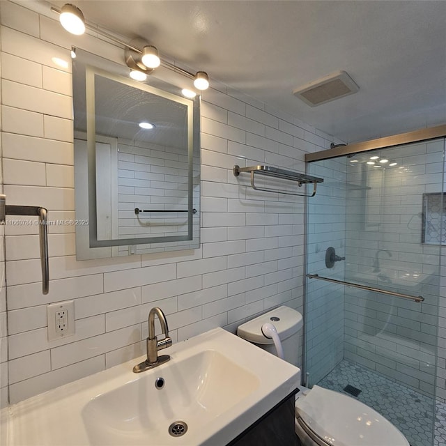 bathroom featuring tile walls, a shower with shower door, tasteful backsplash, toilet, and vanity