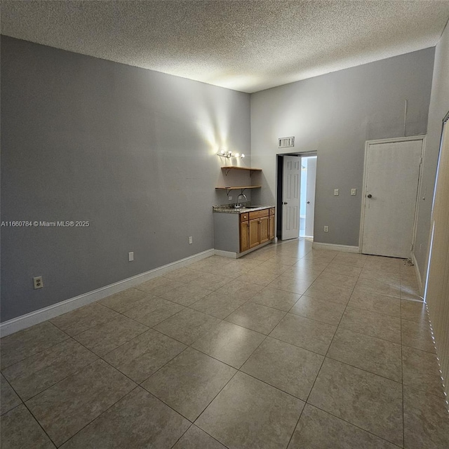 tiled empty room with sink and a textured ceiling