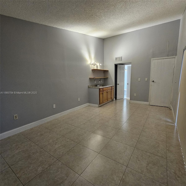 1182 W 37th Ter Unit 11, Hialeah, FL 33012 - spare room with a high ceiling, visible vents, light tile patterned floors, baseboards, and a textured ceiling