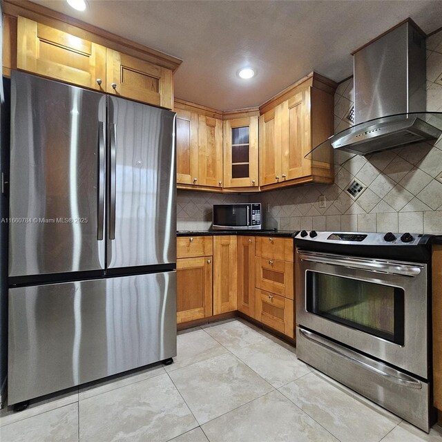 kitchen with wall chimney exhaust hood, stainless steel appliances, decorative backsplash, and light tile patterned floors