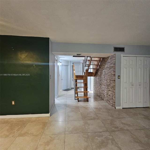 hall with light tile patterned floors and a textured ceiling