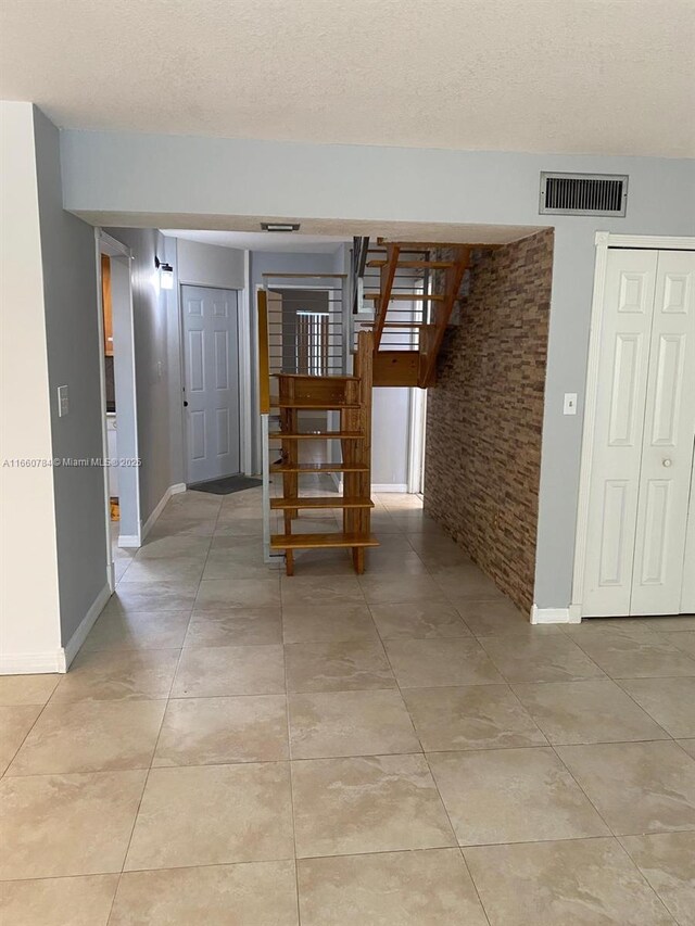 empty room with light tile patterned floors and a textured ceiling