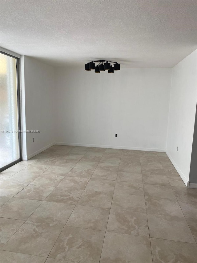 spare room featuring a textured ceiling and baseboards