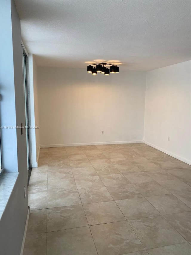 1182 W 37th Ter Unit 11, Hialeah, FL 33012 - empty room with baseboards, a textured ceiling, and light tile patterned floors