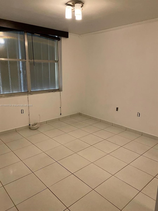 spare room with baseboards and light tile patterned floors