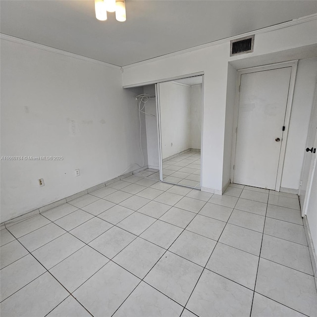 unfurnished bedroom with ornamental molding, a closet, visible vents, and light tile patterned floors