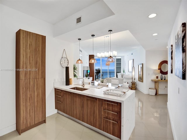 kitchen featuring hanging light fixtures, a water view, light tile patterned flooring, kitchen peninsula, and sink