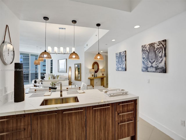 kitchen with light stone counters, hanging light fixtures, light tile patterned floors, and sink