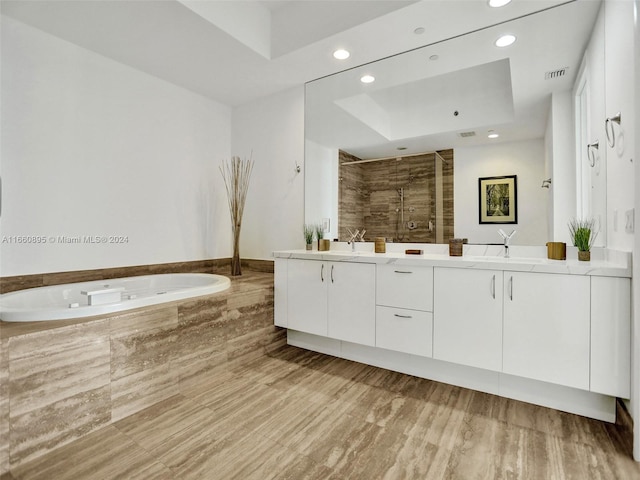 bathroom with shower with separate bathtub, vanity, a tray ceiling, and hardwood / wood-style flooring