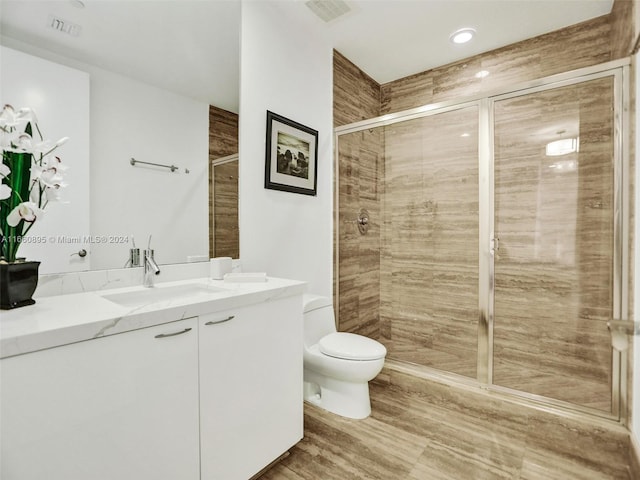 bathroom featuring a shower with shower door, vanity, and toilet