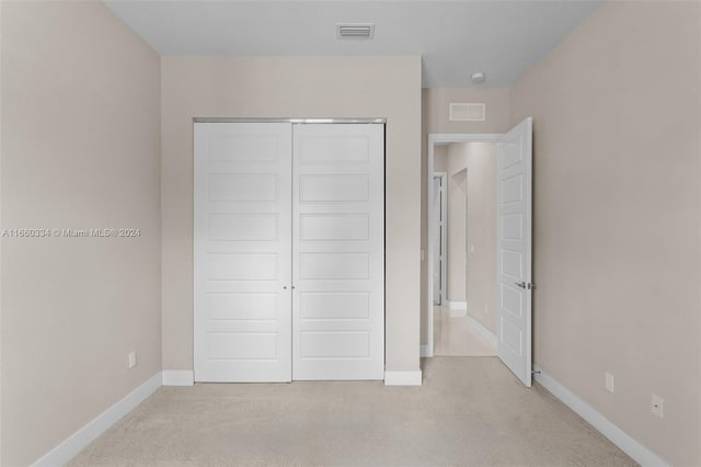 unfurnished bedroom featuring light carpet and a closet