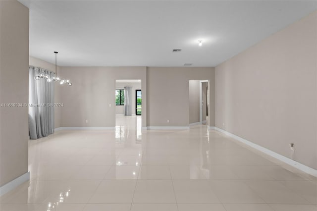 spare room featuring a chandelier and light tile patterned floors