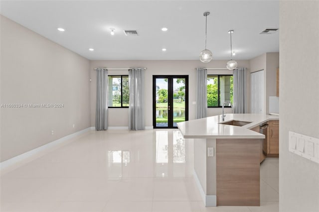 kitchen featuring sink, light tile patterned floors, decorative light fixtures, french doors, and stainless steel dishwasher