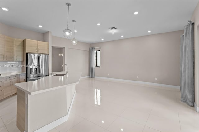 kitchen with a kitchen island with sink, stainless steel fridge with ice dispenser, sink, decorative light fixtures, and light brown cabinetry