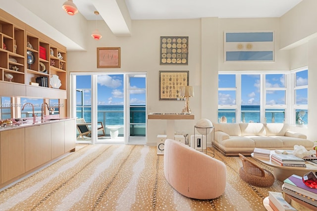 living area with a water view and a towering ceiling