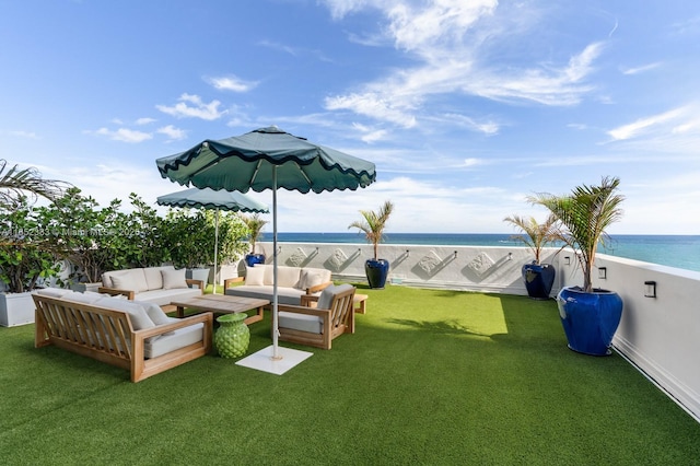 view of yard with outdoor lounge area, a water view, and a beach view