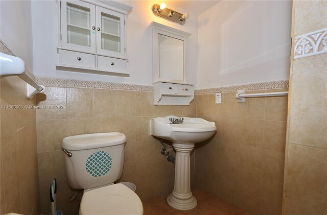 bathroom with tile walls and toilet