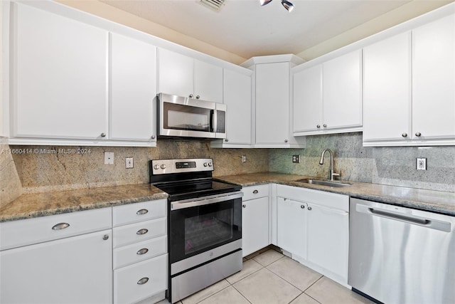 kitchen featuring tasteful backsplash, sink, white cabinets, stainless steel appliances, and light tile patterned floors