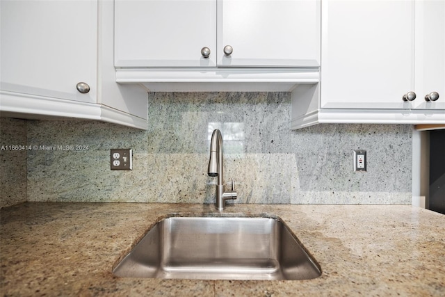 kitchen with light stone countertops, backsplash, sink, and white cabinets