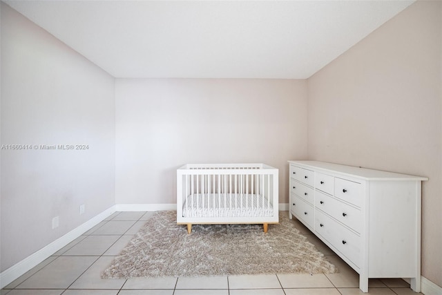 unfurnished bedroom featuring a nursery area and light tile patterned floors