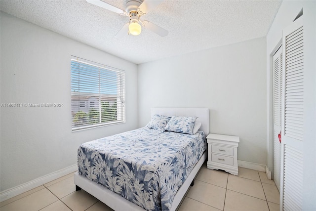 bedroom with ceiling fan, light tile patterned flooring, a closet, and a textured ceiling