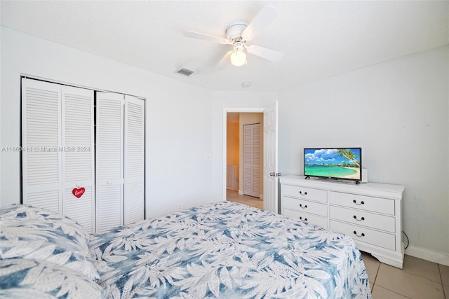 bedroom featuring ceiling fan, a textured ceiling, a closet, and light tile patterned floors