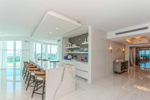 bar with white cabinets, light stone counters, and sink