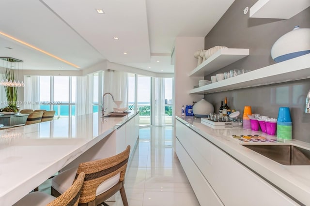 kitchen featuring a water view, a wealth of natural light, white cabinetry, and sink