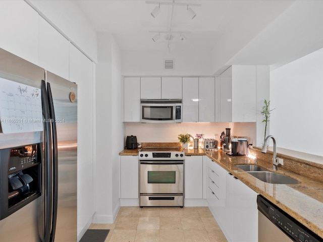 kitchen featuring light stone countertops, white cabinetry, sink, rail lighting, and stainless steel appliances