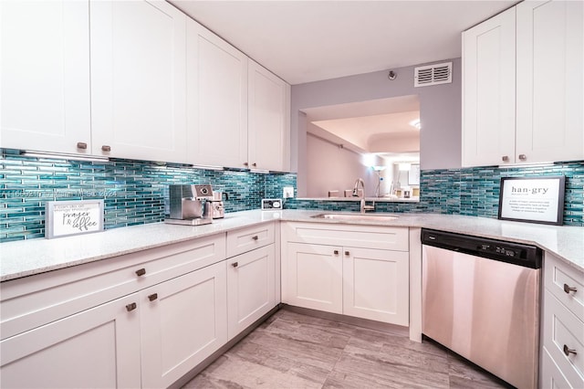 kitchen with light wood-type flooring, dishwasher, sink, white cabinets, and light stone countertops