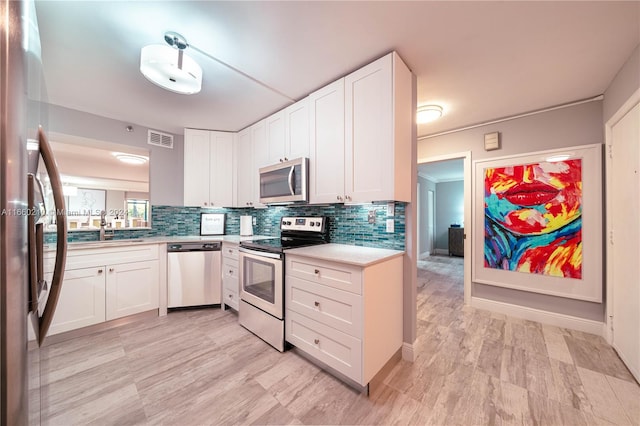 kitchen with appliances with stainless steel finishes, backsplash, and white cabinets