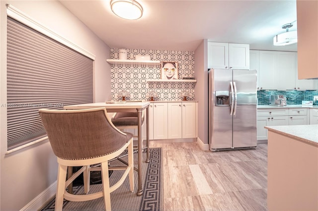 kitchen with white cabinets, stainless steel fridge, and tasteful backsplash