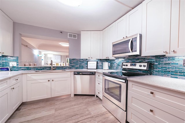 kitchen featuring light stone counters, sink, backsplash, white cabinetry, and stainless steel appliances