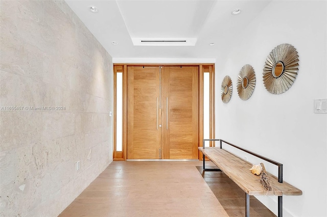 hallway with recessed lighting, a raised ceiling, and wood finished floors