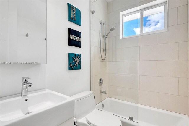 full bathroom featuring tiled shower / bath combo, toilet, and sink